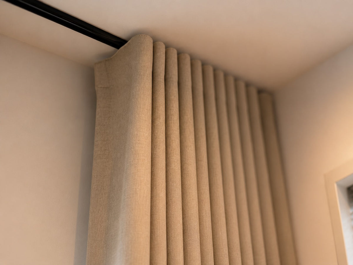 Beige gordijnen met regelmatige plooien aan een zwarte plafondrail