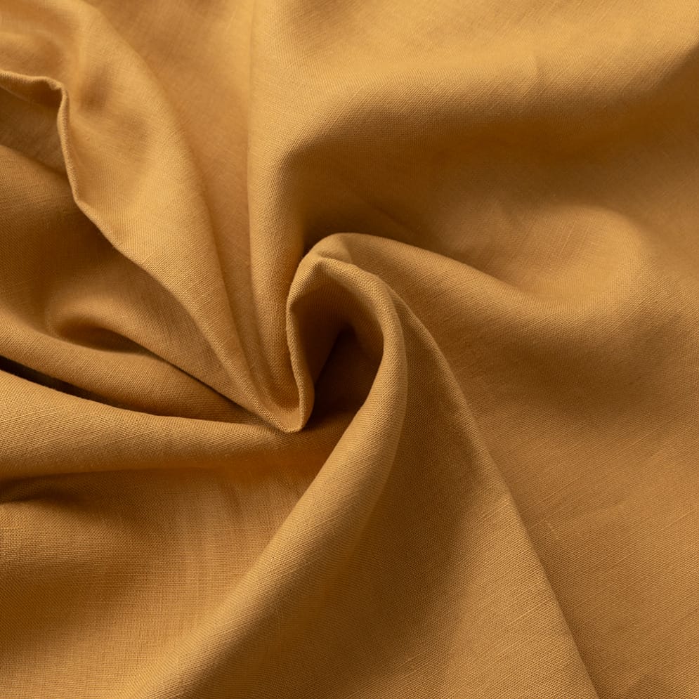 Detail van ambergele stof met glans en plooien.