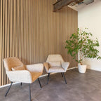Lamellenwand achter twee stoelen en een plant.