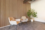 Lamellenwand achter twee stoelen en een plant.