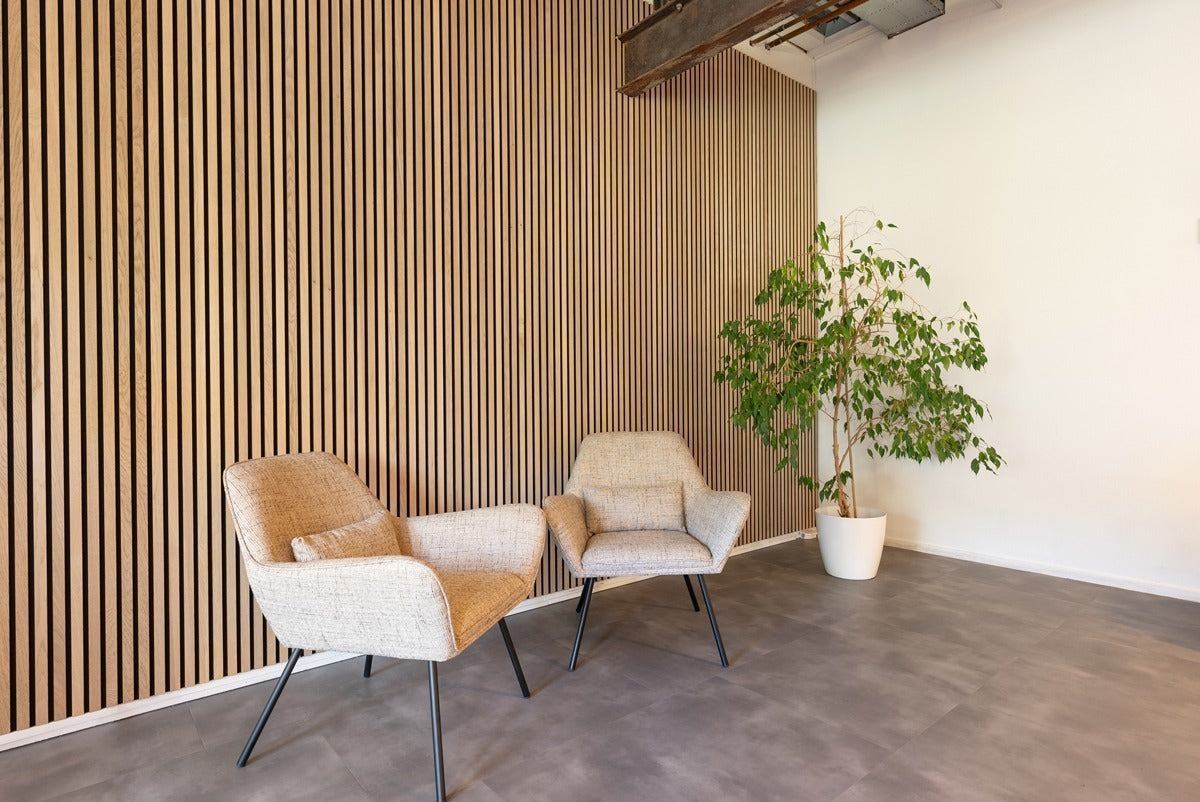 Lamellenwand achter twee stoelen en een plant.
