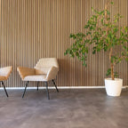Lamellenwand achter twee stoelen en een grote plant in een witte pot.