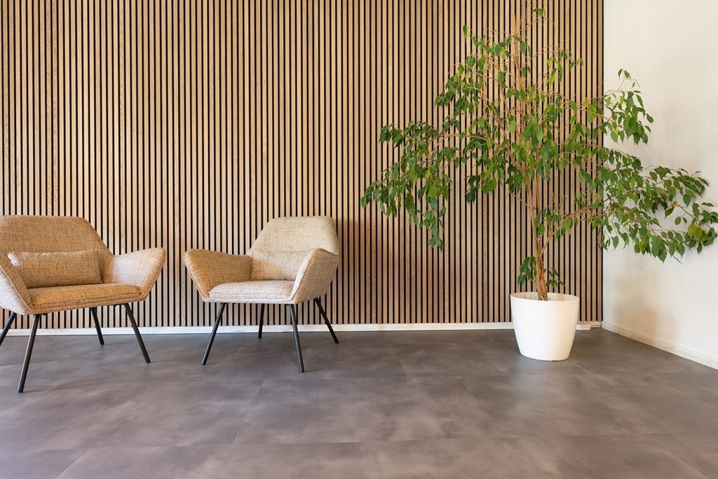 Lamellenwand achter twee stoelen en een grote plant in een witte pot.