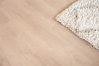 Vloer met rechte planken naast een vloerkleed.