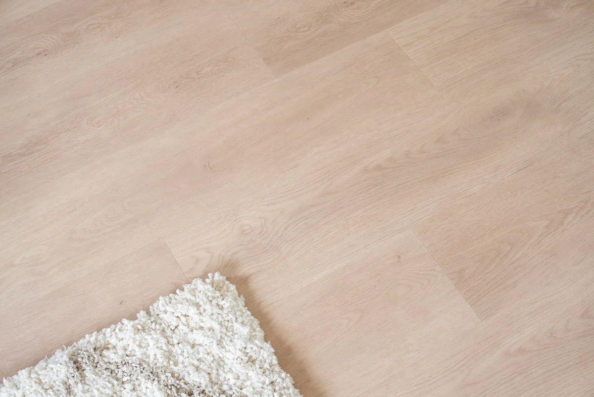 Vloer met rechte planken naast een vloerkleed.