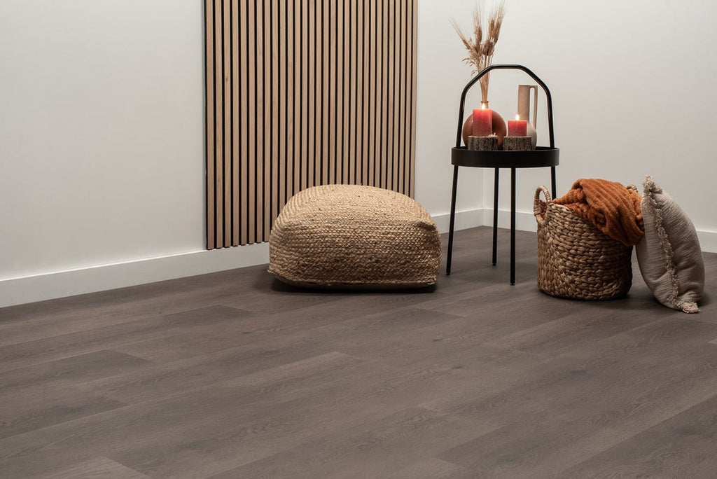 Vloer met rechte planken naast een poef en bijzettafel.