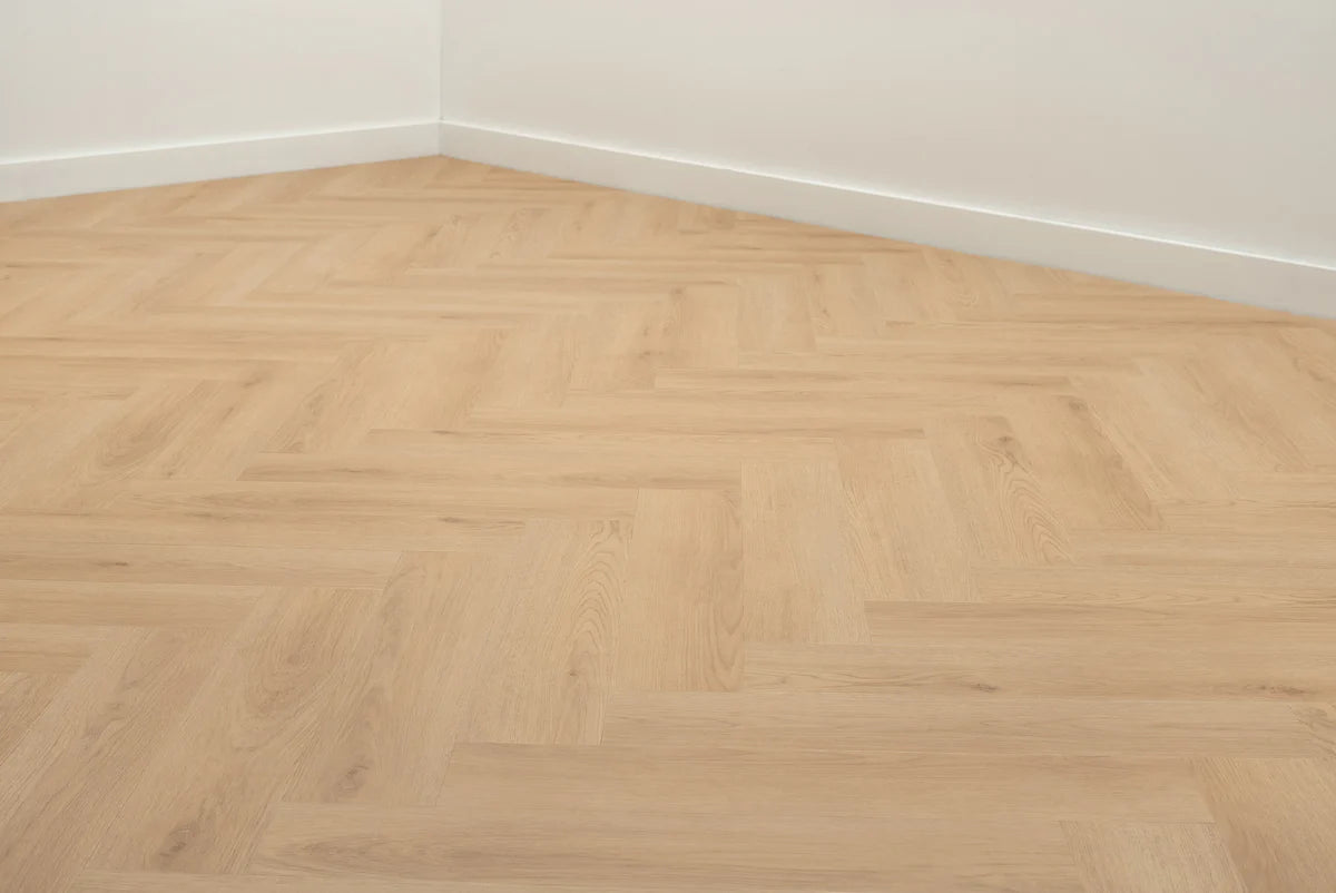 Lichte visgraatvloer in een kamer met witte plinten.