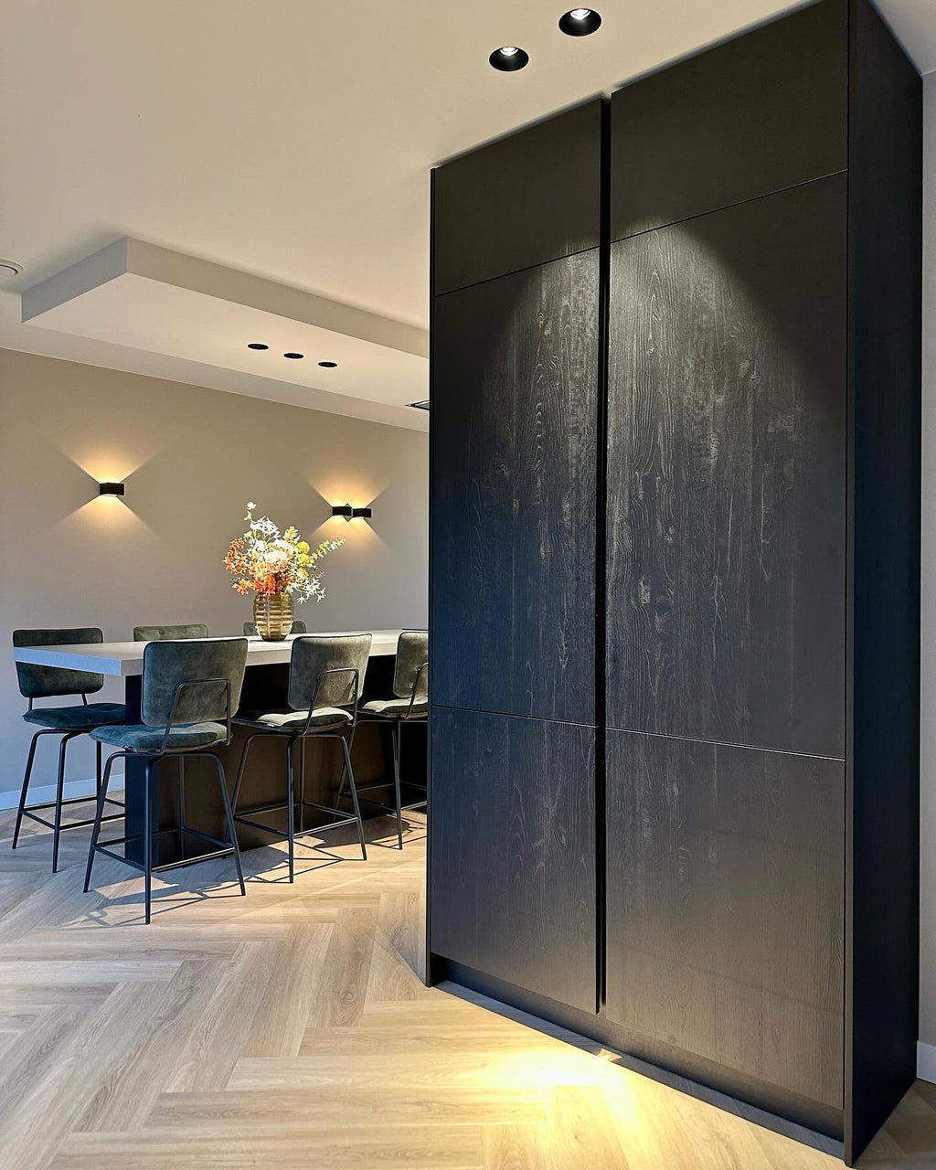 Interieur met een donker wandmeubel en een lichte visgraatvloer.