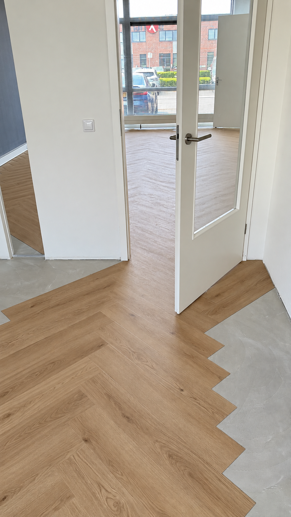 Walvisgraatvloer wordt doorgelegd bij een deur met glas van 050-IT