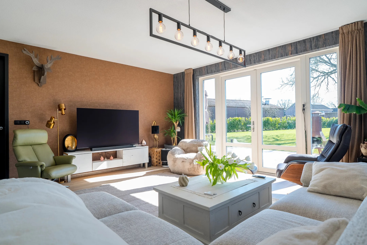 Woonkamer met houtlookvloer langs het kleed en de tuindeuren in Westerbork