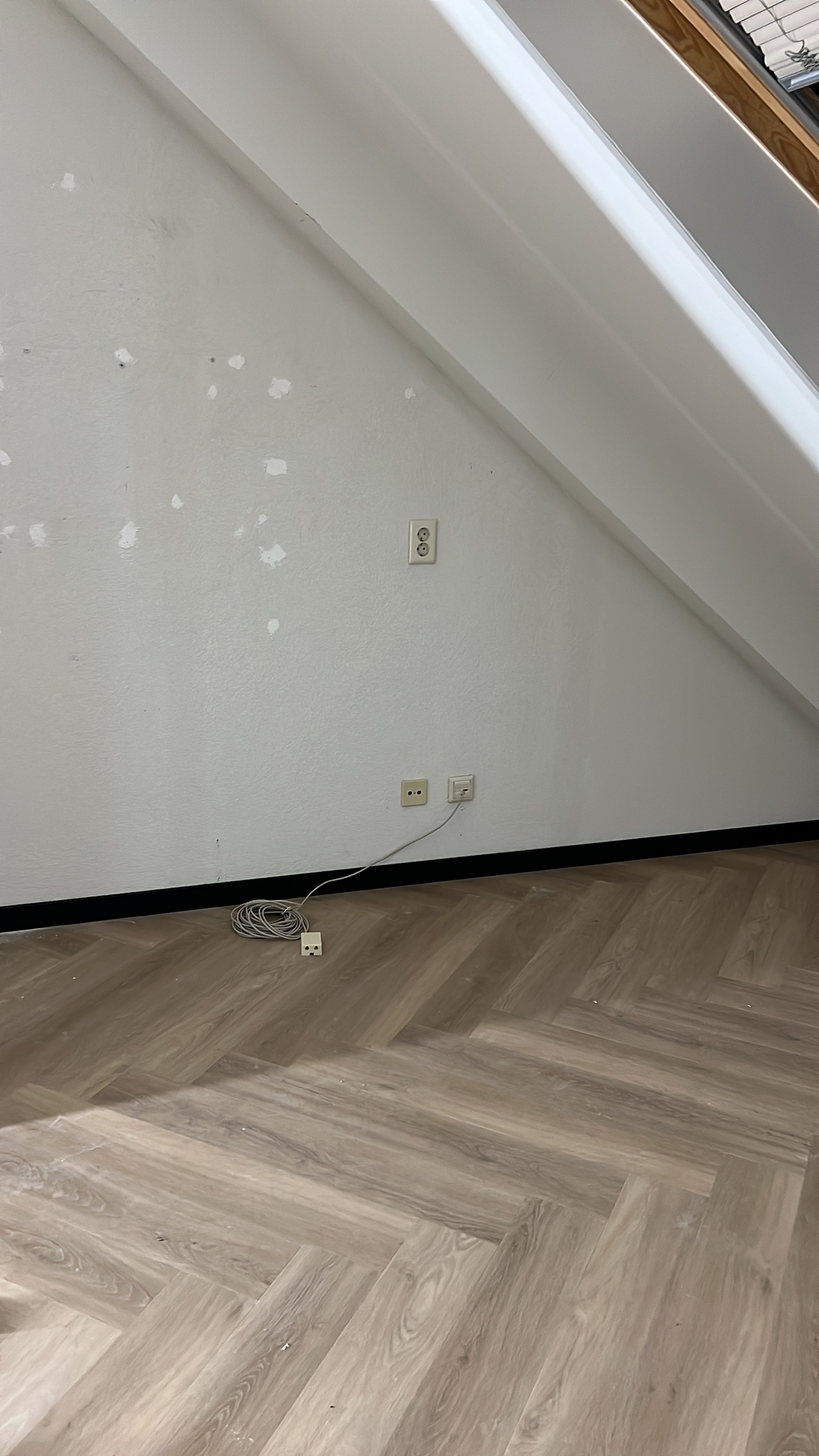 Visgraatvloer en zwarte plint langs de schuine wand in Zuidlaren