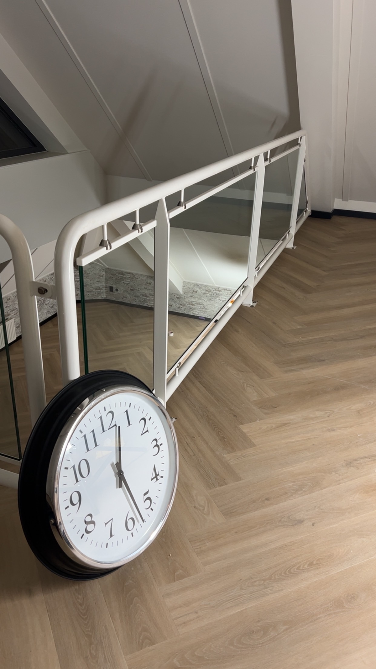 Visgraatvloer op de overloop bij de witte glasbalustrade in Zuidlaren