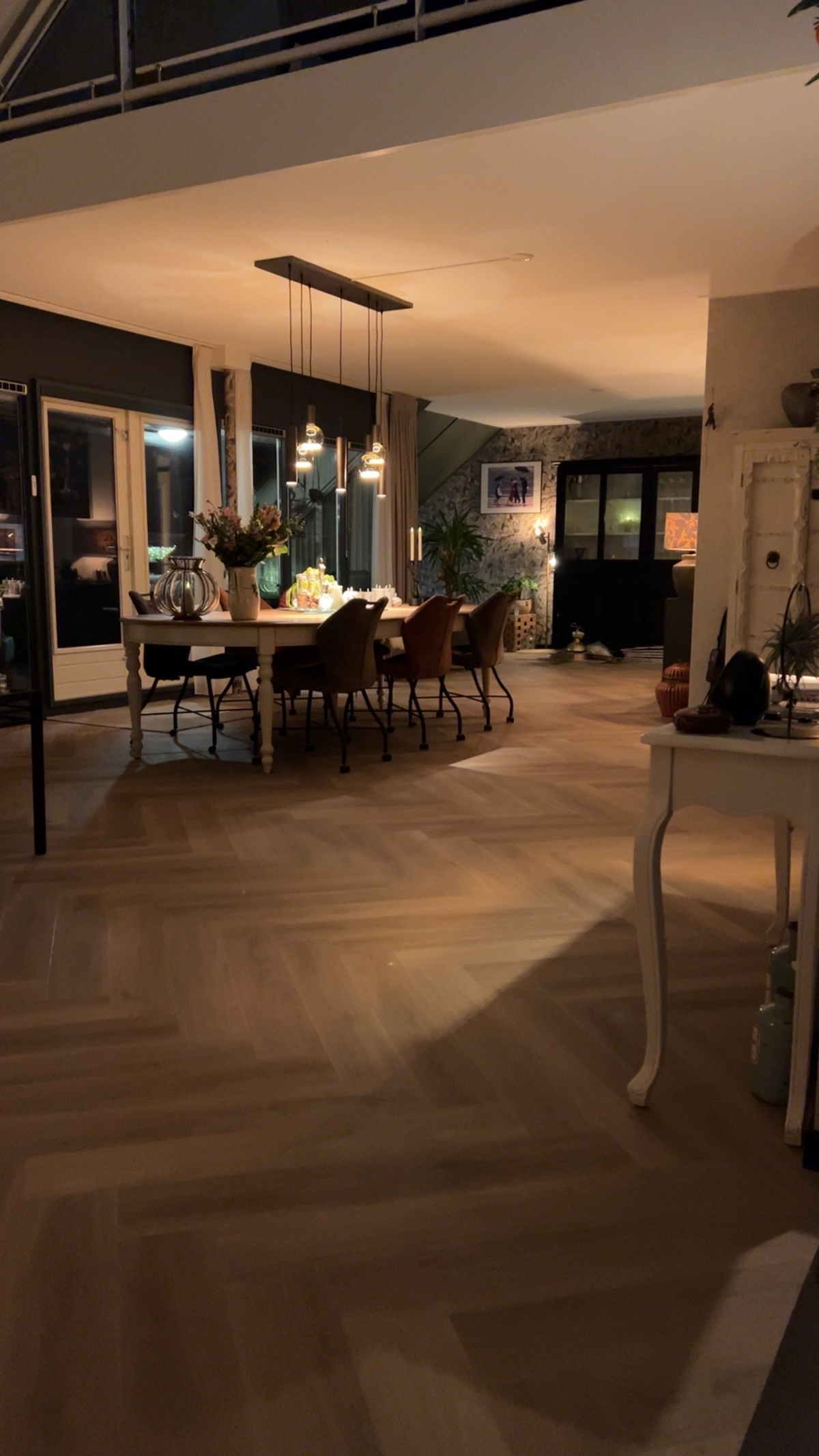 Ingerichte woonruimte met visgraatvloer en hoge vide in avondlicht in Zuidlaren