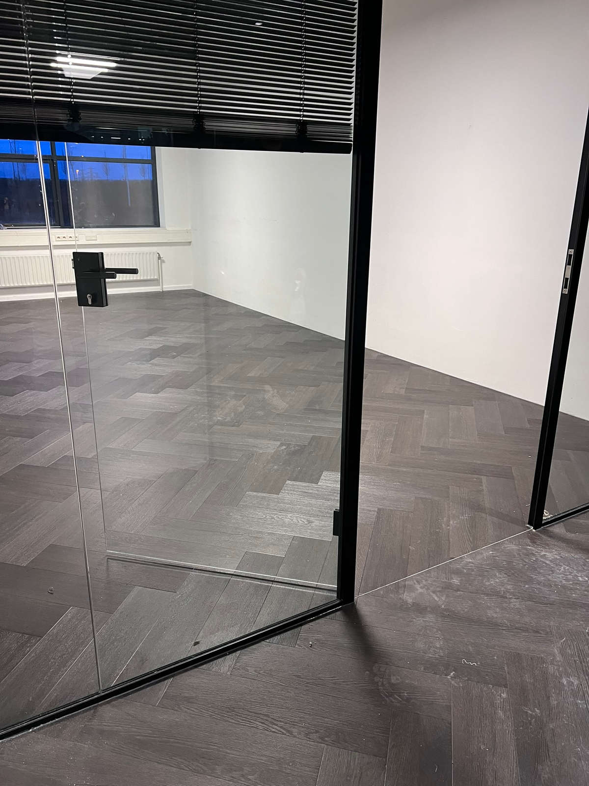 Detail van de visgraatvloer en glazen deuren bij Kwadraat
