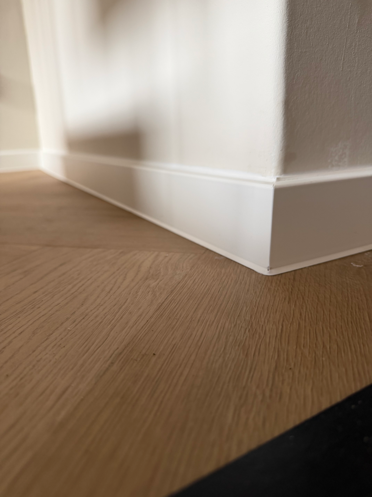 Laag detail van de witte plint langs de visgraatvloer