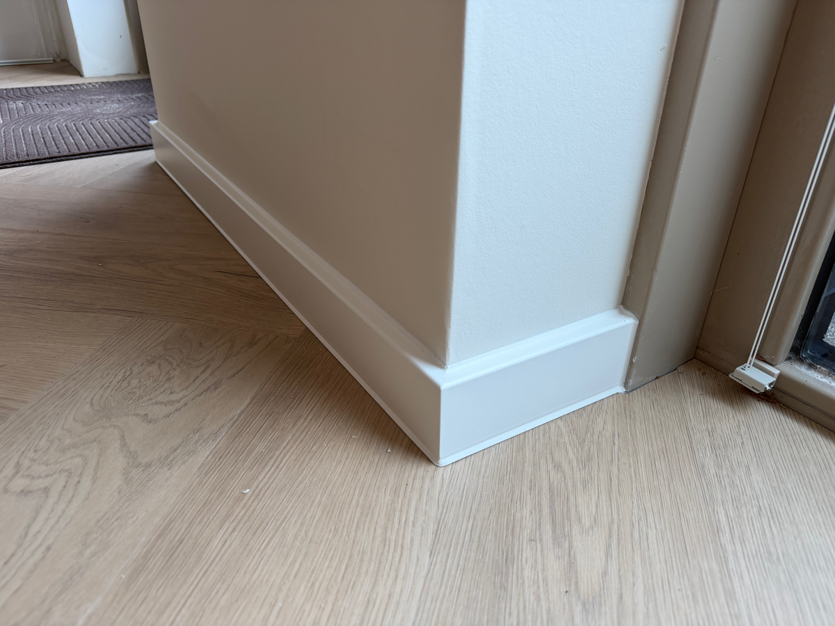 Witte plint en vloeraansluiting bij een deuropening