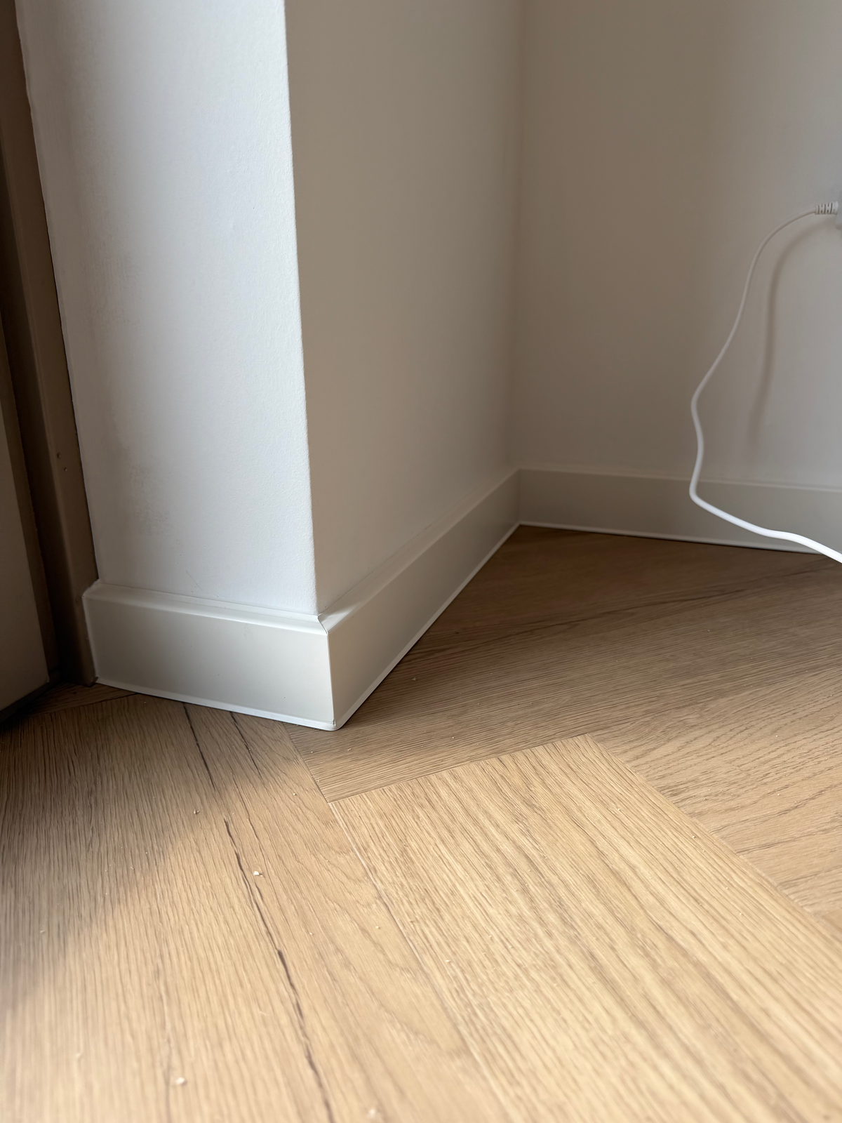 Witte plint rond de kolom naast de visgraatvloer