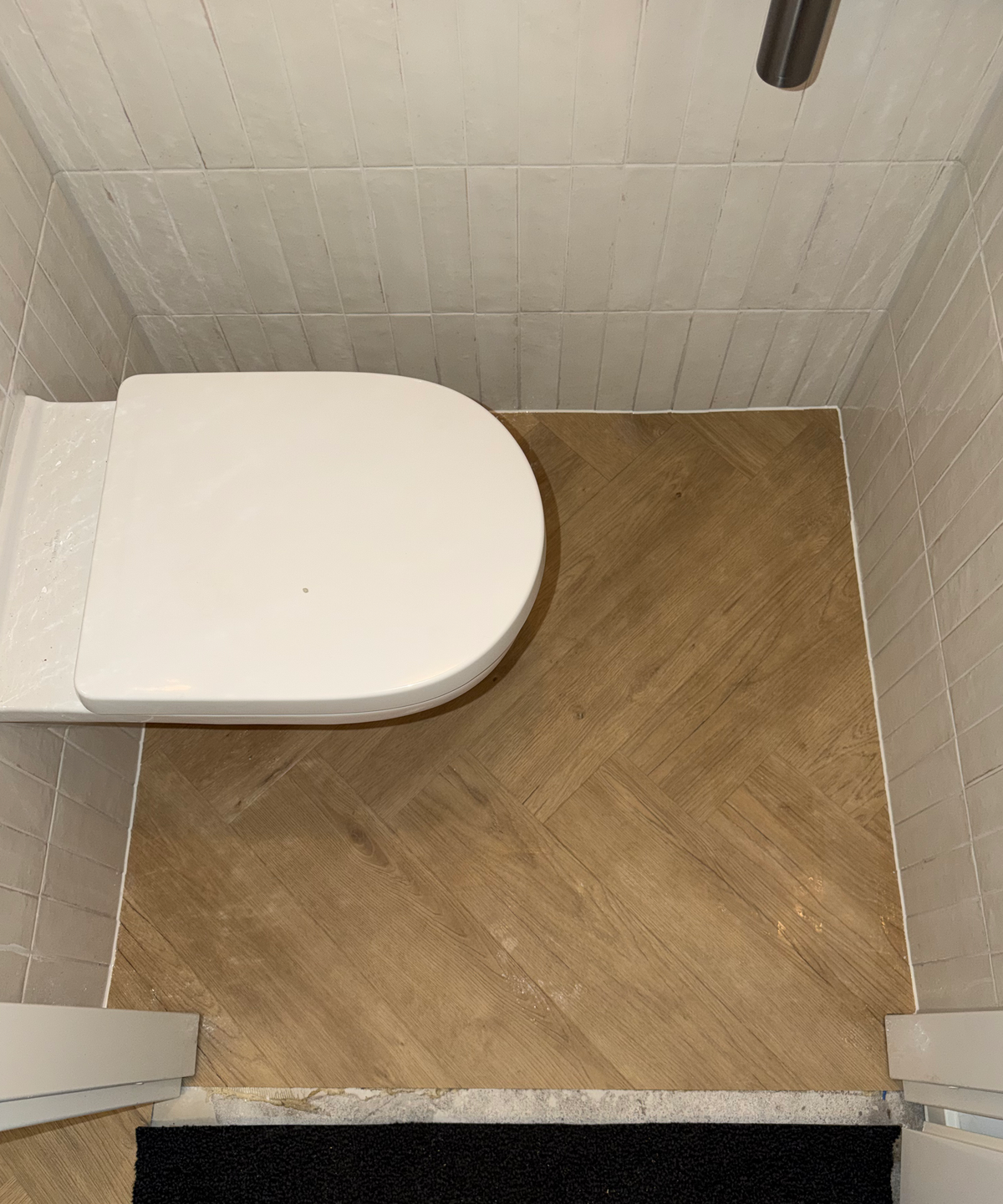 Visgraatvloer met witte randafwerking in het toilet in Meerstad