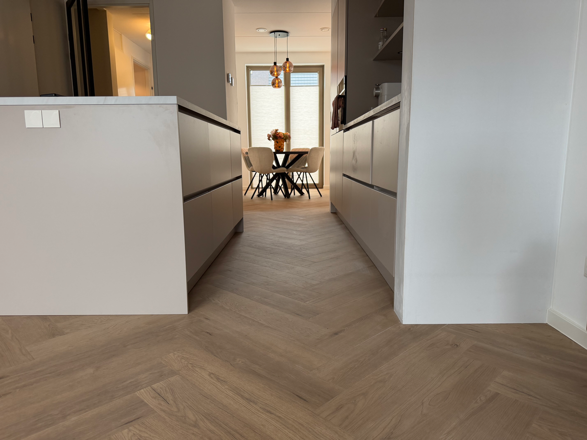 Brede doorkijk over de visgraatvloer door de keuken in Meerstad