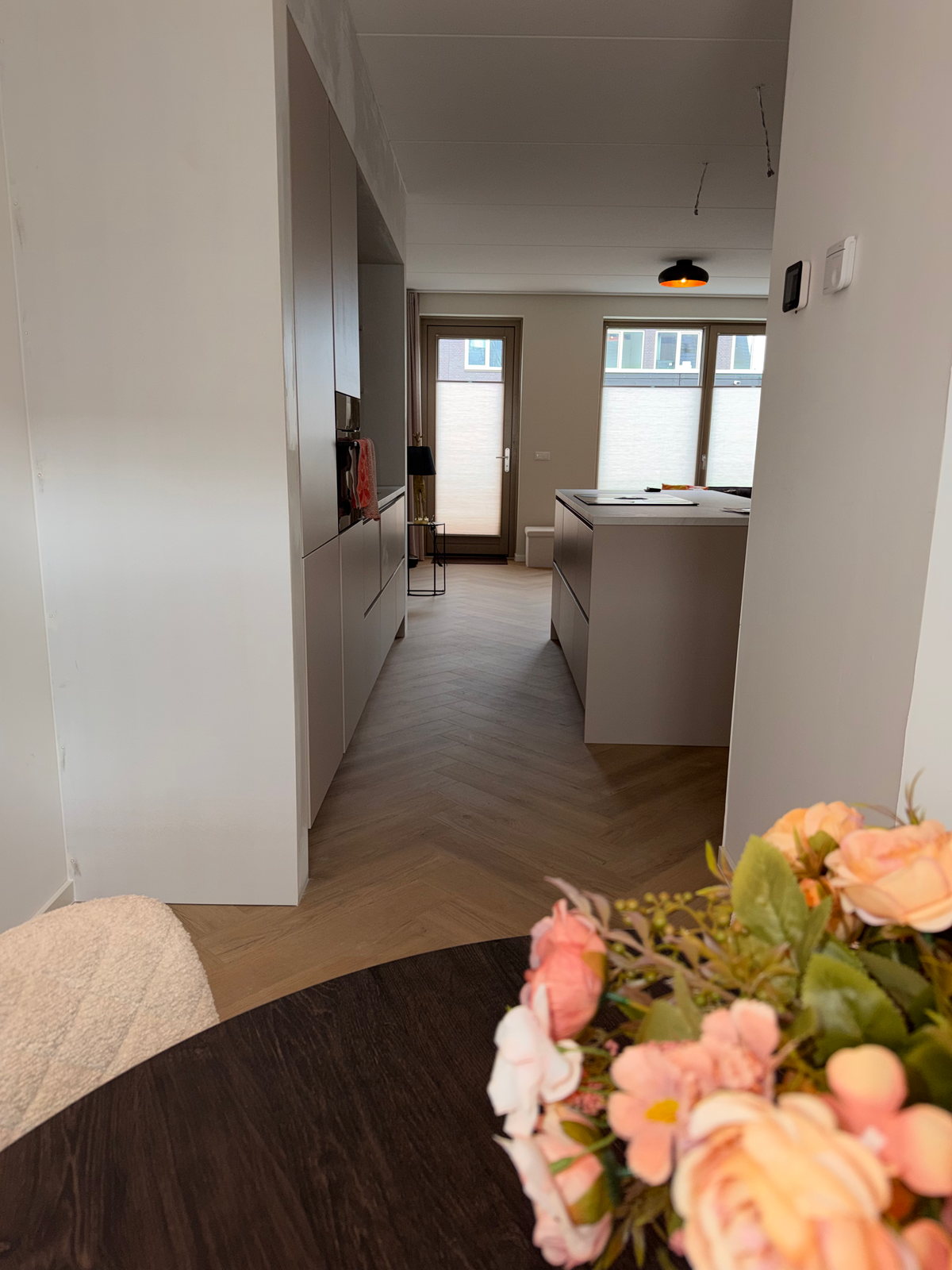 Doorkijk vanuit de eethoek naar keuken en visgraatvloer in Meerstad