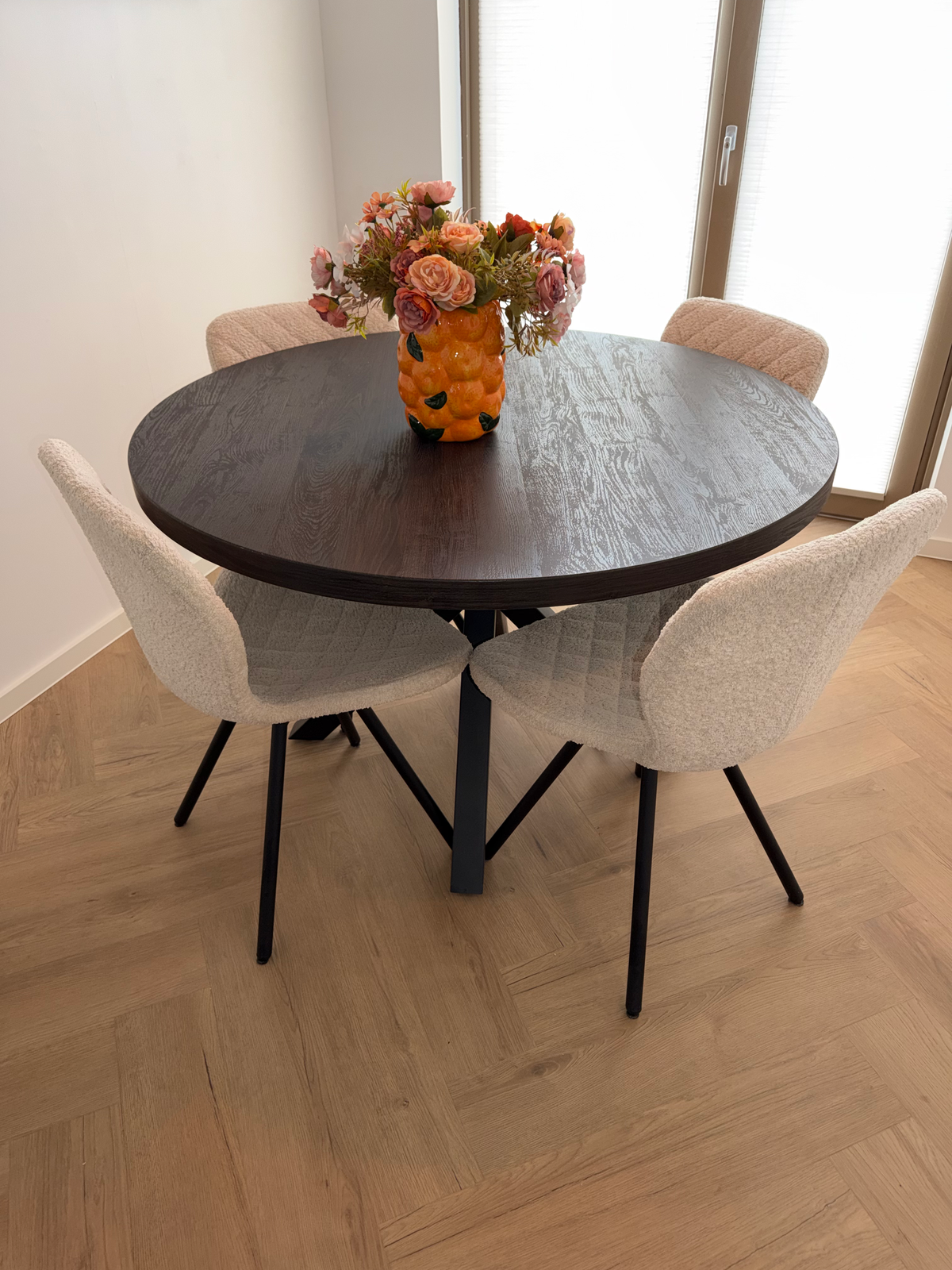 Visgraatvloer tussen de stoelen onder de ronde eettafel in Meerstad