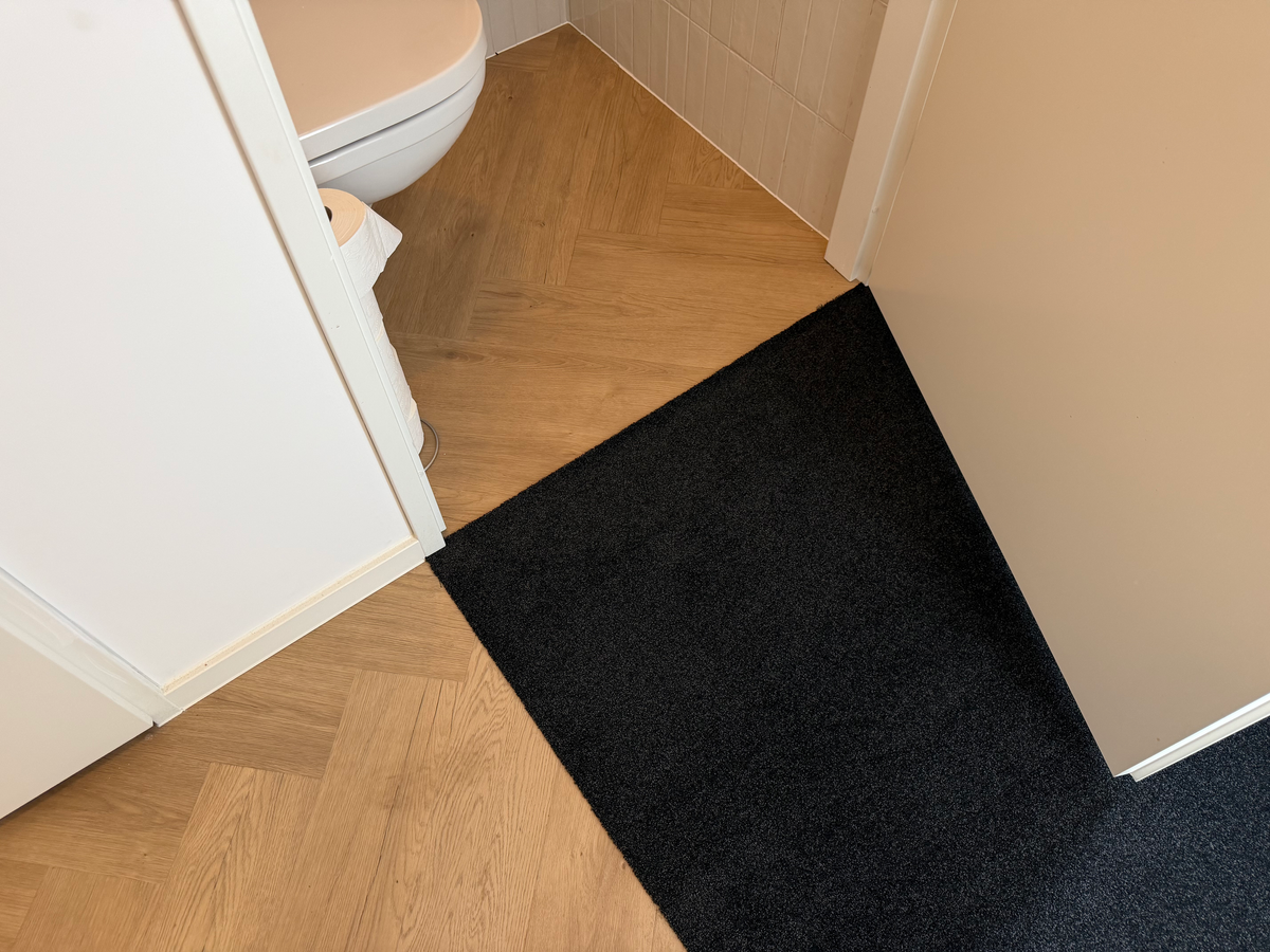 Schoonloopmat met aansluiting op de visgraatvloer bij het toilet in Meerstad