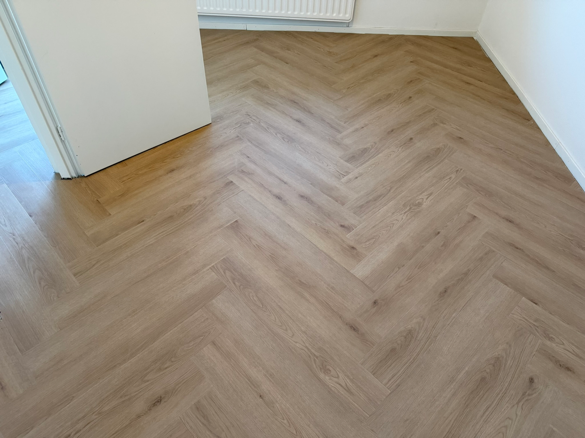Detail van de aangelegde Bryde Bruin klik-walvisgraatvloer aan de Veldspaat