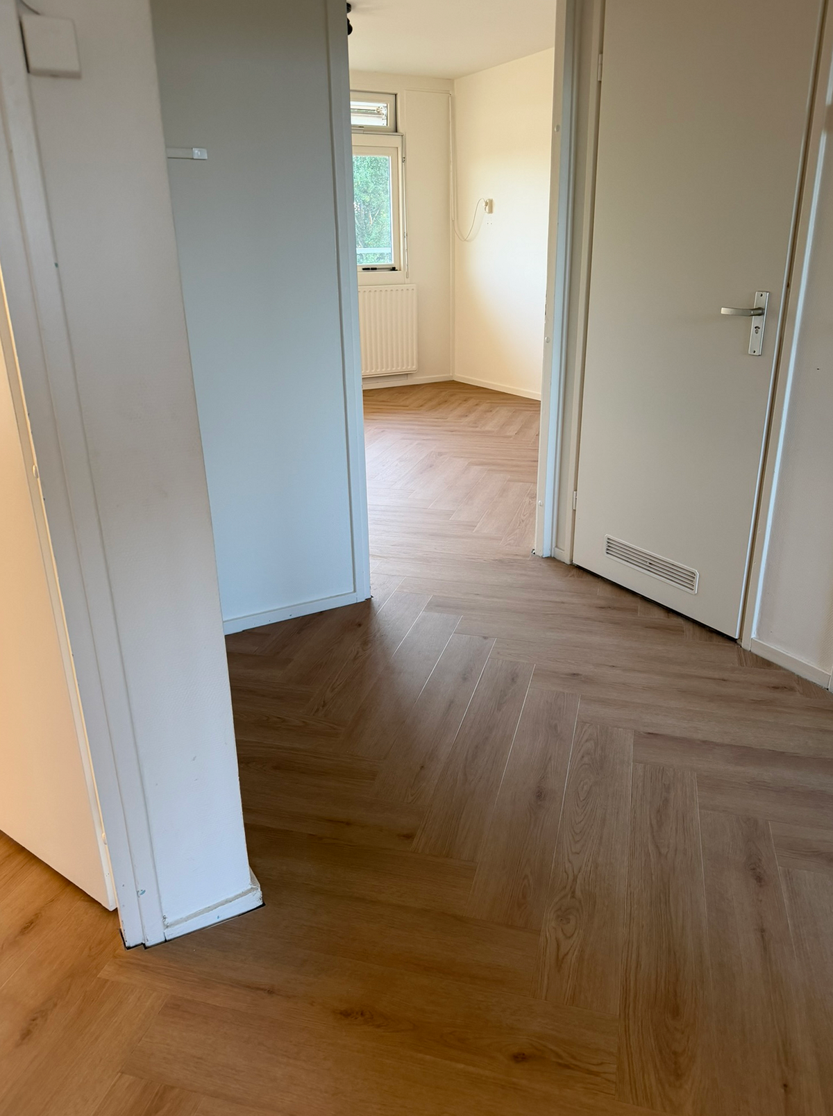 Walvisgraatvloer die doorloopt vanuit de hal naar de aangrenzende kamer