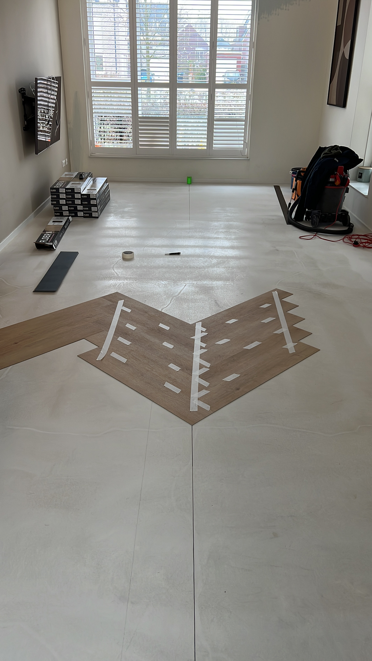 Eerste banen walvisgraat met uitzetlijn en tape in de woonkamer in Meerstad