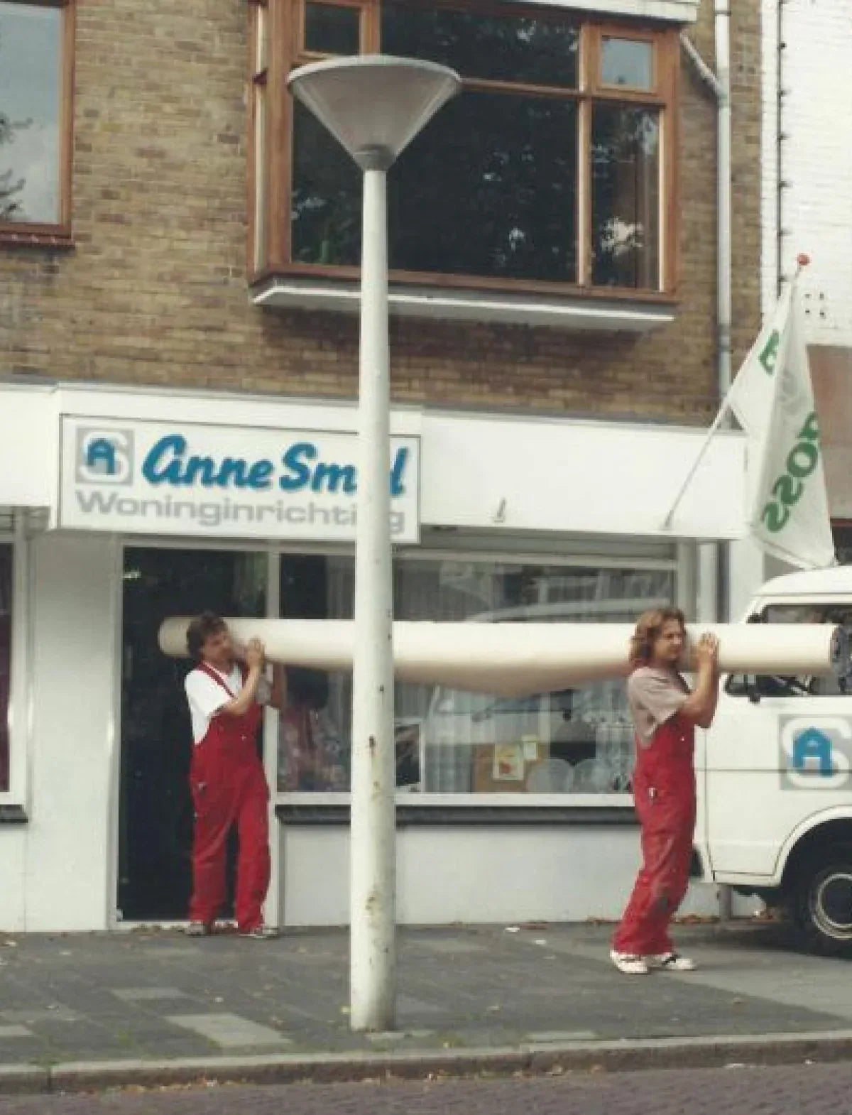 Historische foto bij Anne Smid Woninginrichting: samen een rol tapijt dragen